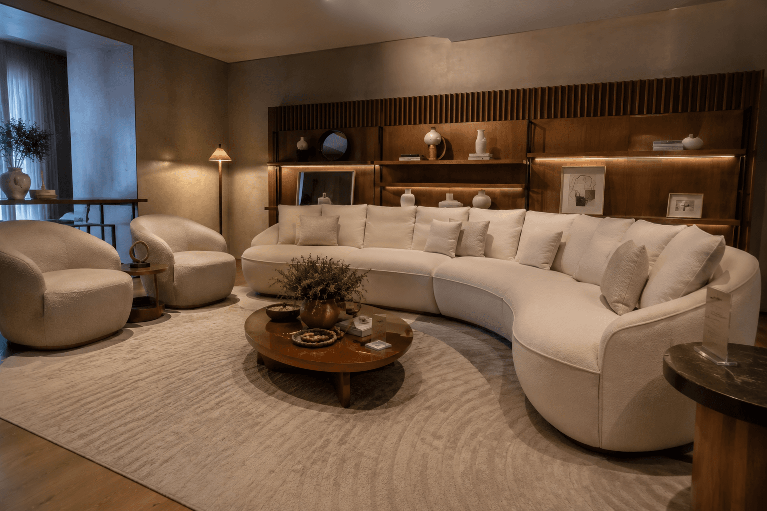 Sala de estar sofisticada com sofá curvo bouclé creme, poltronas arredondadas e estante iluminada